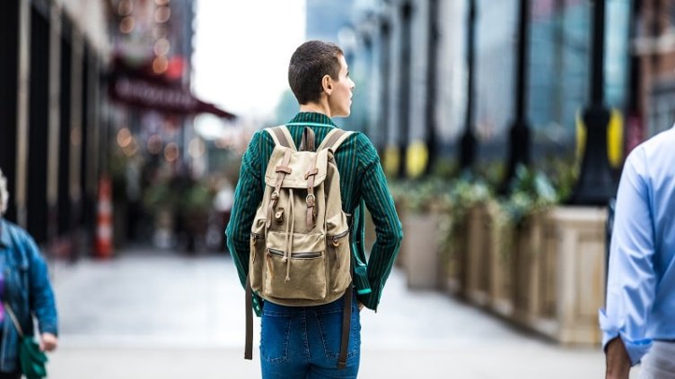Young boy with a backpack and looking at the shops while walking
