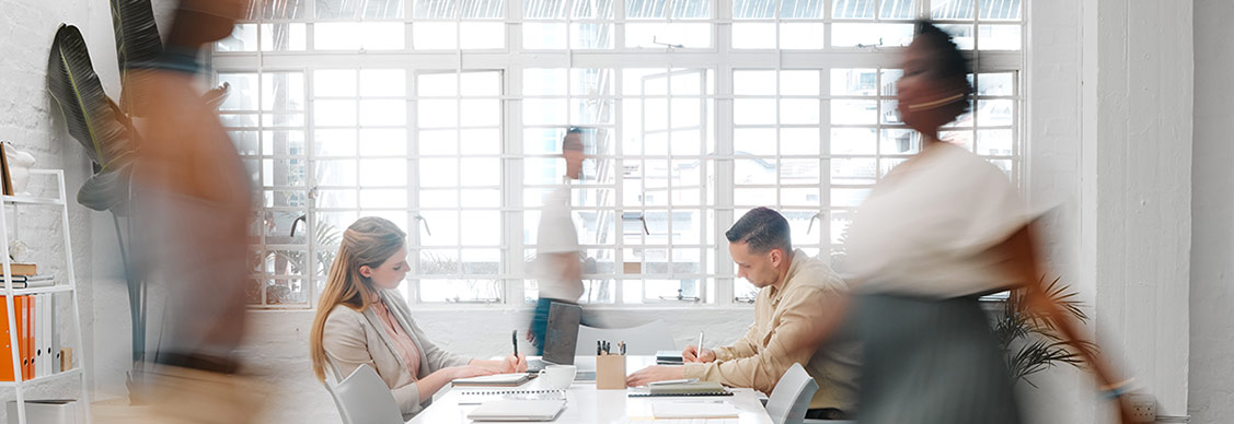 blurry image with people moving and working in a workplace space
