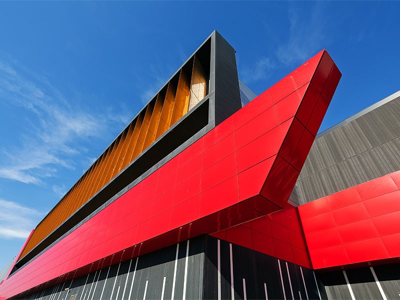 details of aluminum facade with colorful red and orange panels on large shopping mall