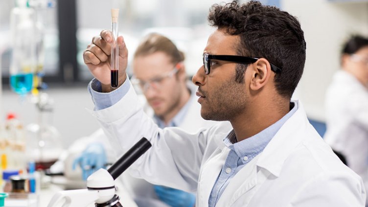Side view of young scientist in eyeglasses looking at test tube in research laboratory; Shutterstock ID 629140007; PO: US900-1800-164500-9998-Americas-9900-; Job: 345227; Client: Boston; Other: 345227_NTL_MKTG_Life Sciences_Relocation Planning and Management Brochure