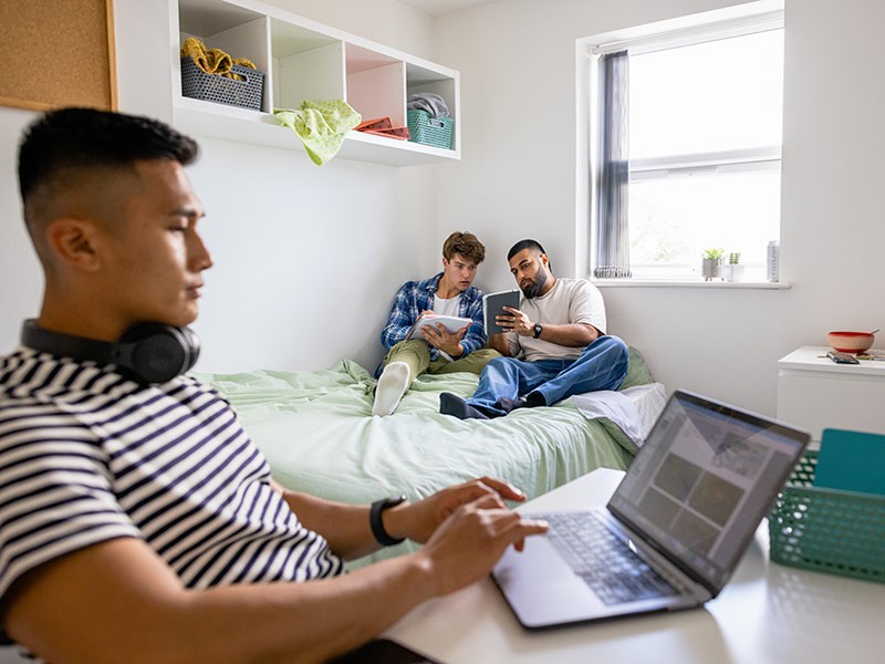 Group of male college students in shared house kitchen washing up and hanging out