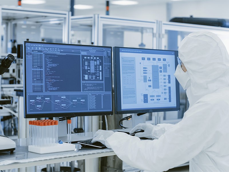 Healthcare professional in hazmat suit using computer