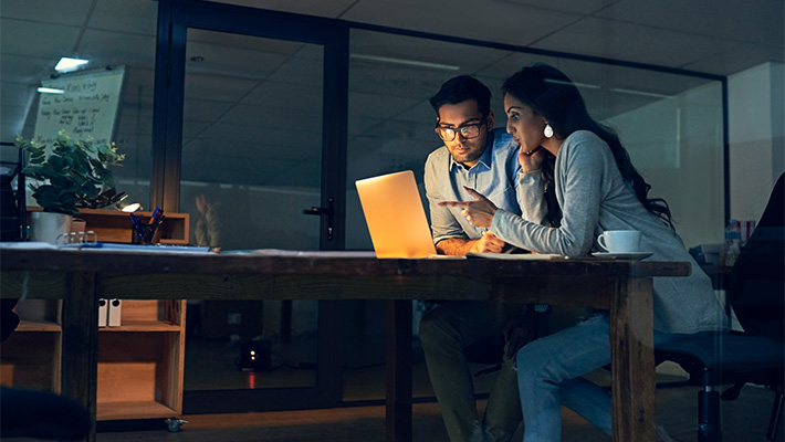 Cropped shot of two colleagues working late on a laptop in an office