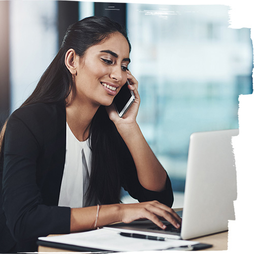 Young woman talking on the mobile phone while using her laptop