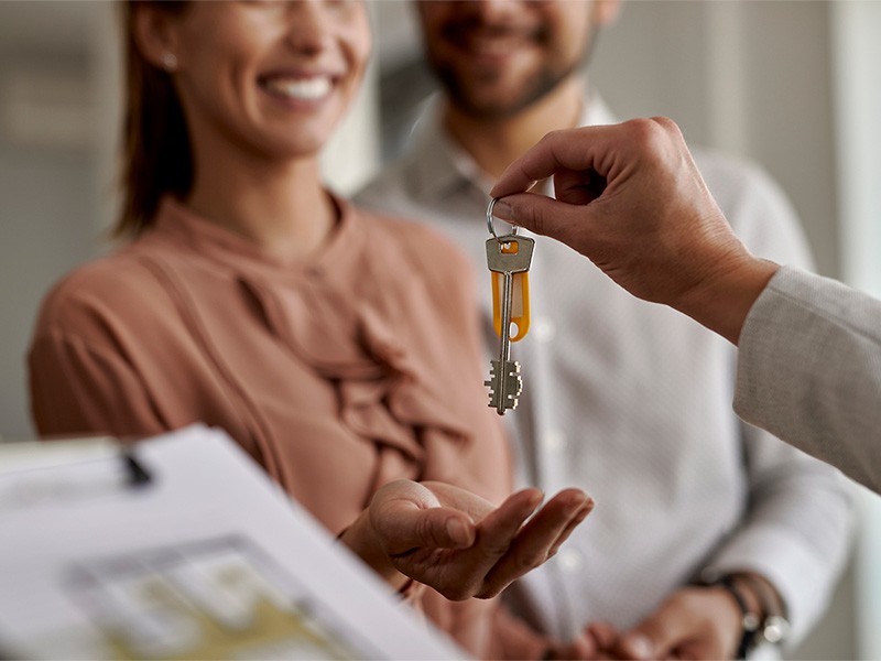 Close-up of real estate agent giving new house keys to a couple.