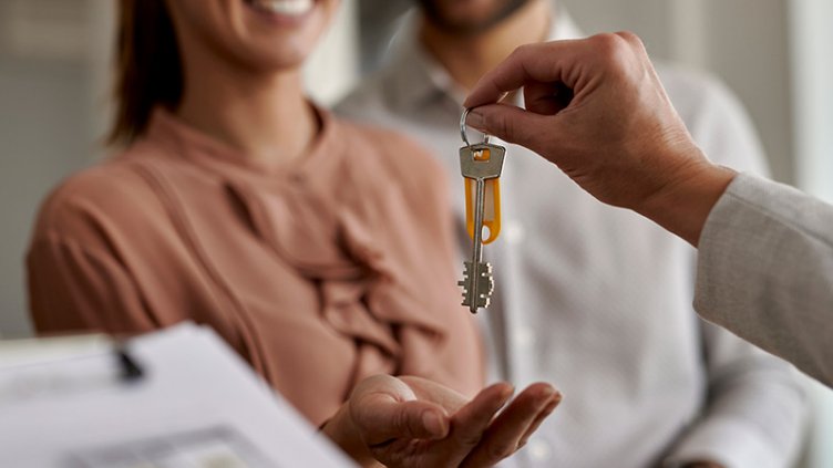 Close-up of real estate agent giving new house keys to a couple.