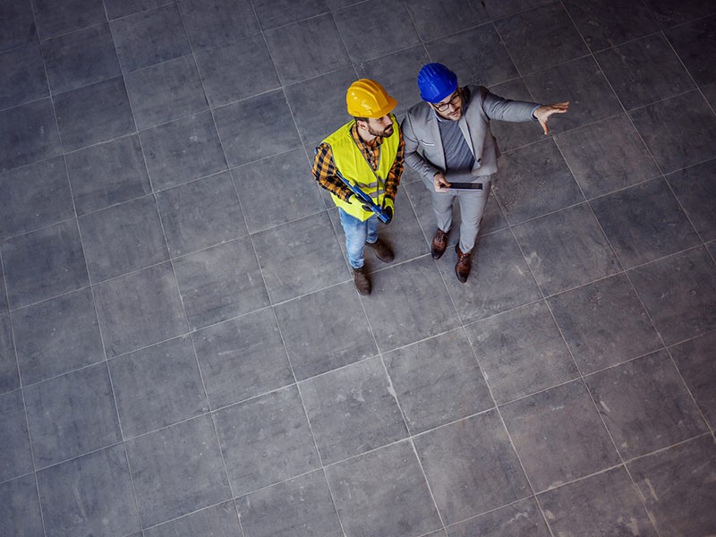 Top view of supervisor with helmet on head in suit standing with construction worker