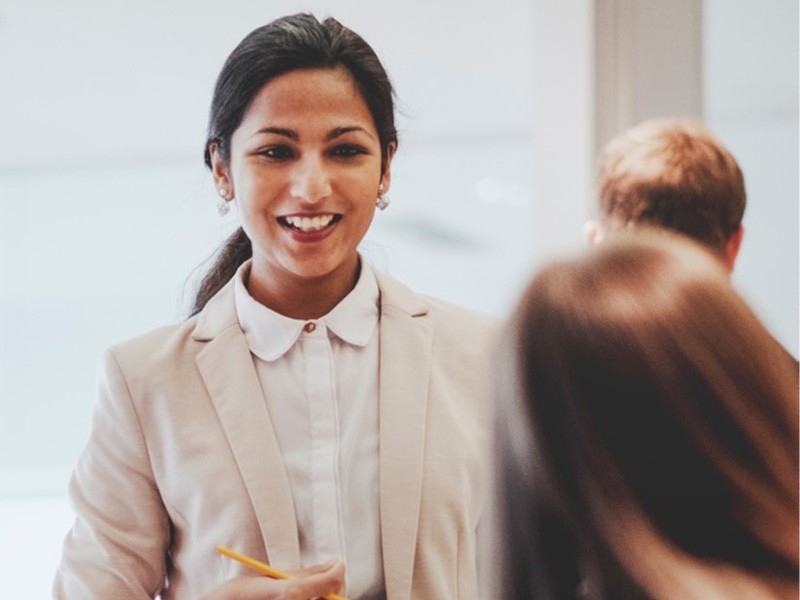 Brunet corporate woman smiling at her colleague