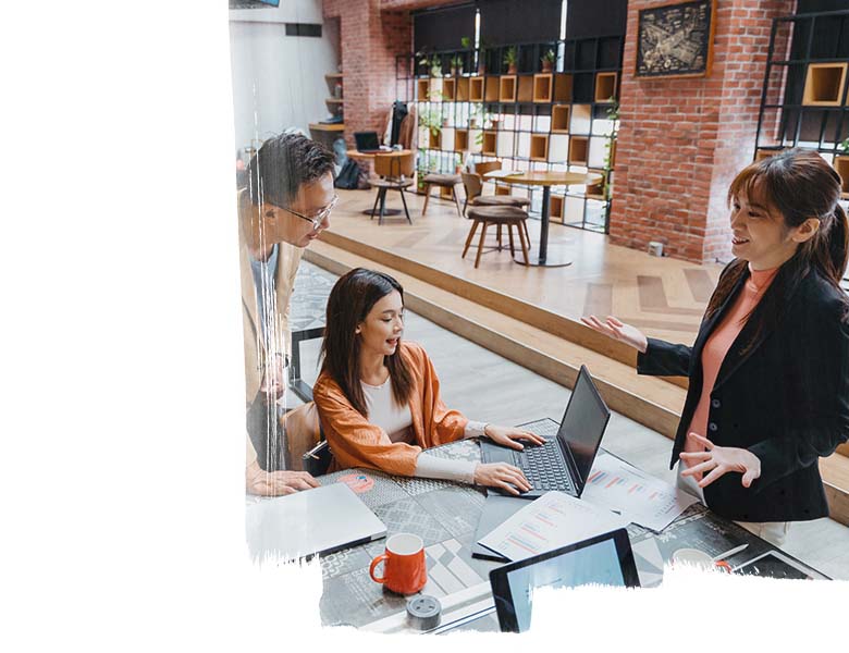 One man and three ladies in a collaborative office space, having a work group discussion 