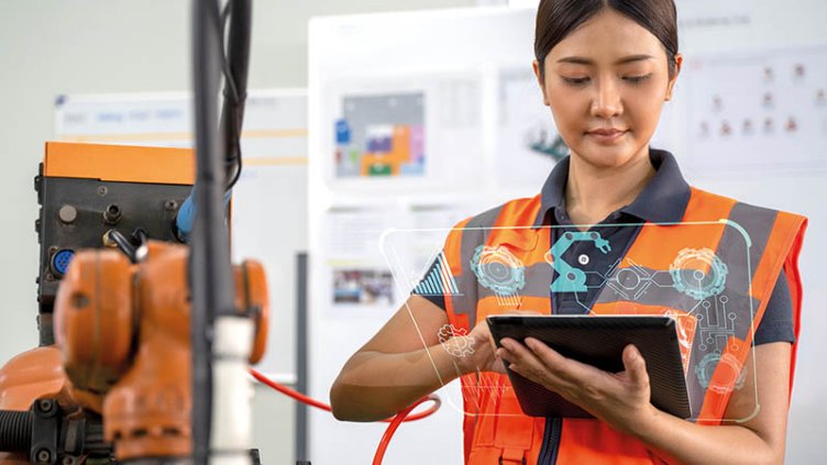 A lady wearing a safety orange vest, at a warehouse, holding a tablet showing automation technologies 