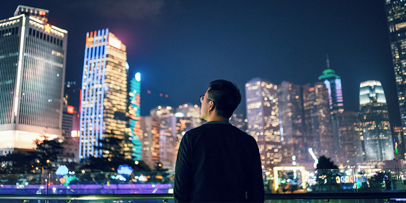 Man looking at a city building at night time