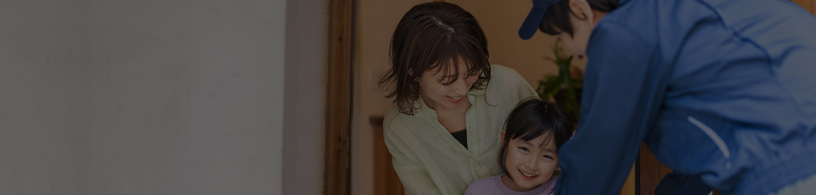 Smiling young woman and her daughter receiving delivery from delivery man at home