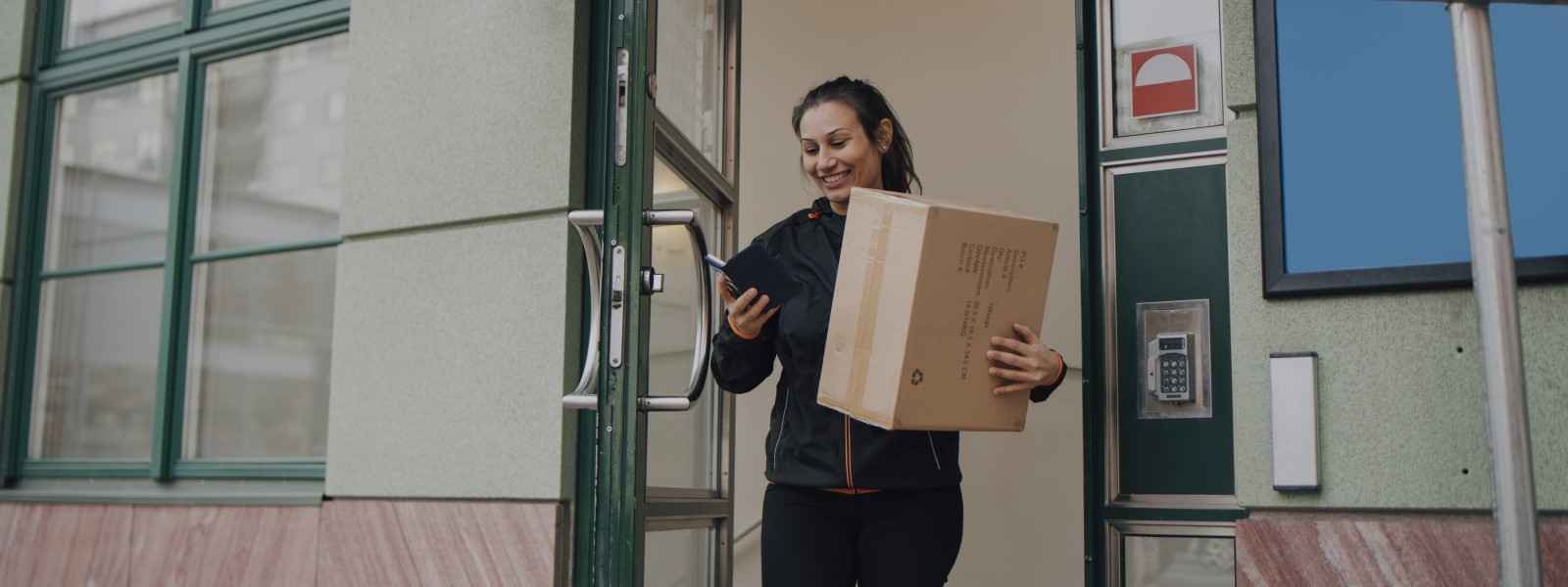 Female leaving a secure building with a delivery package
