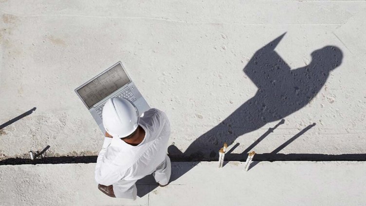Top view of an architect working on his laptop at the construction site