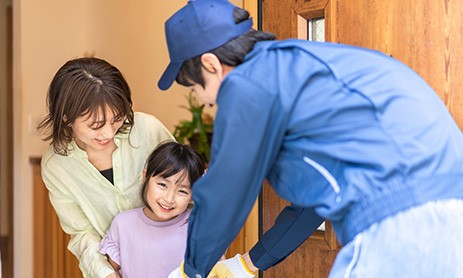 Smiling young woman and her daughter receiving delivery from delivery man at home