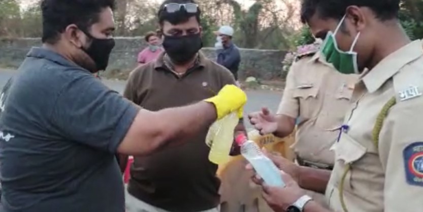 JLL India employee distribute sanitizing gel to policemen at road checkpoints