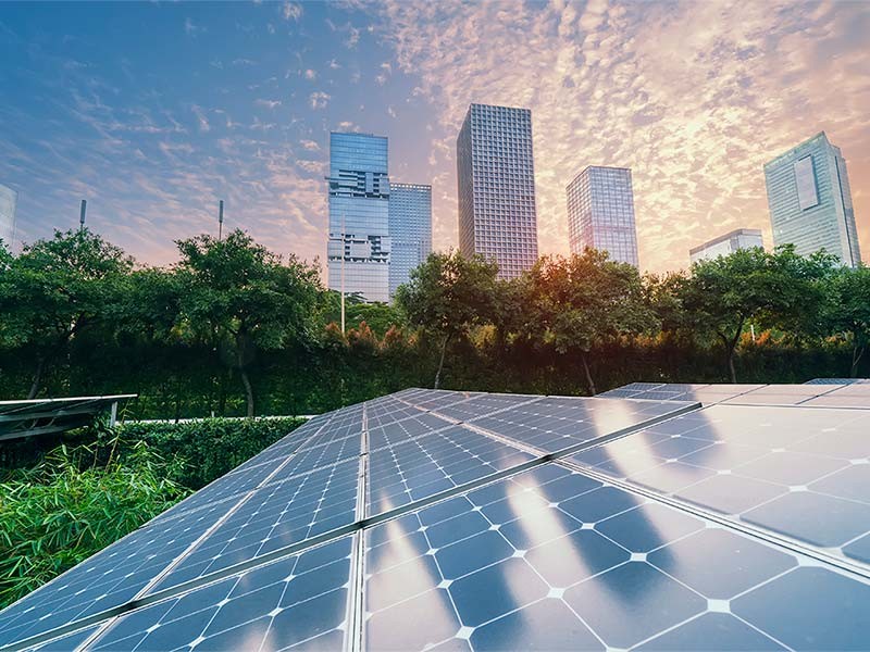 Solar panels and commercial buildings with a sunset backdrop