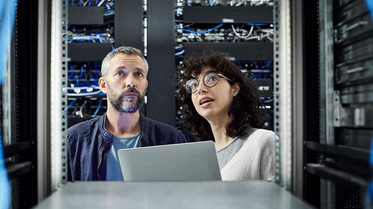 A man and a woman inspecting racks in a data center.