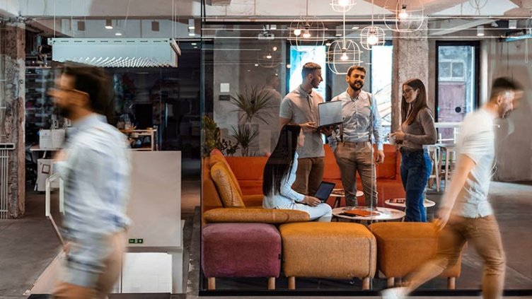 Employees collaborating together in more informal casual office setting with sofa