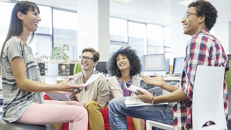 Employees laughing having a conversation while working inside the office