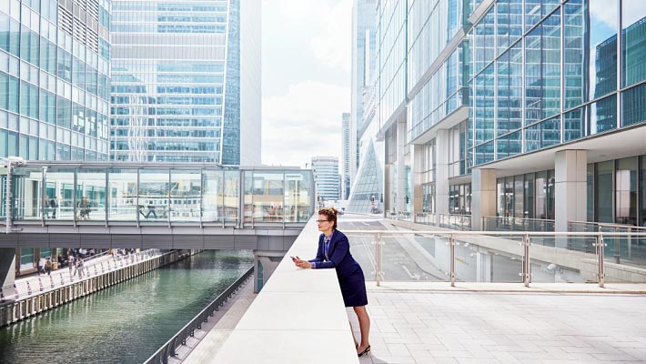 Businesswoman standing in building terrace looking over bridge